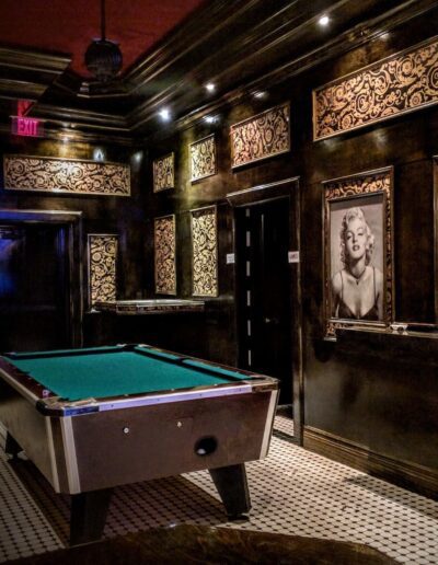 A pool table in an ornate room with framed pictures on the walls.