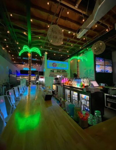 Illuminated bar area with neon lighting and reflective surfaces, projecting a vibrant nightlife ambiance.