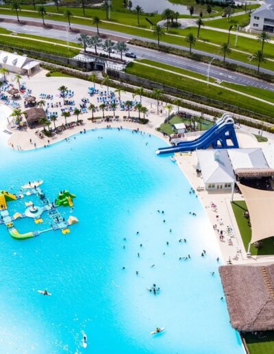 Aerial view of a bustling water park with a large swimming pool, slides, and lounge areas.