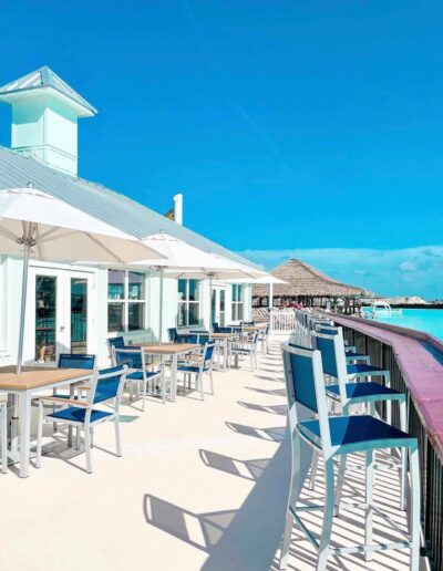 Seaside restaurant with blue chairs and umbrellas on a sunny day.