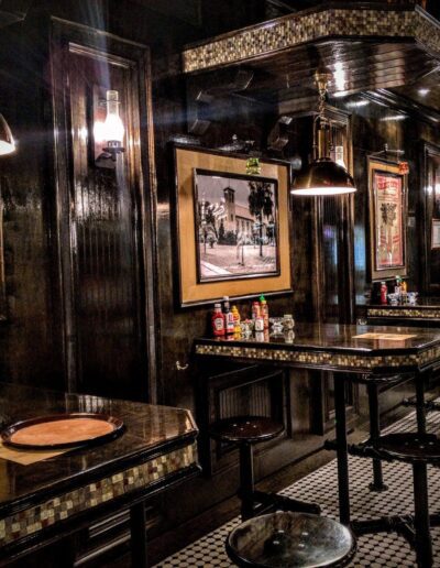 Dimly lit vintage-style diner interior with framed pictures, a bar counter, and classic stools.