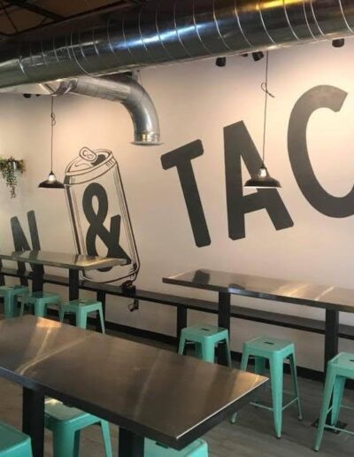 Interior of a casual taco eatery with modern decor and green stools.