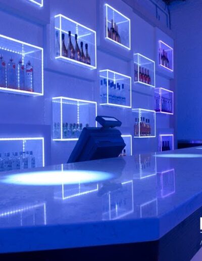 A modern bar with blue led lighting and illuminated shelves displaying bottles.