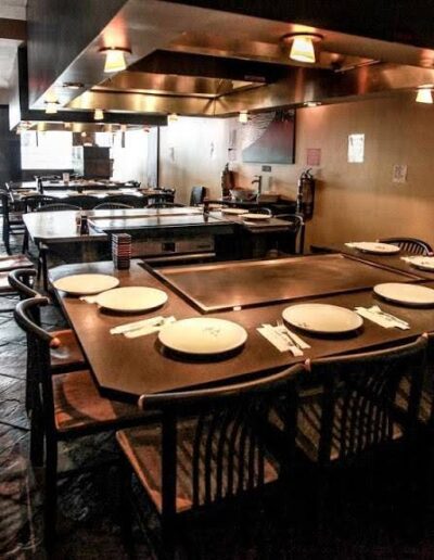 Interior of a dimly lit restaurant with empty tables set for service.