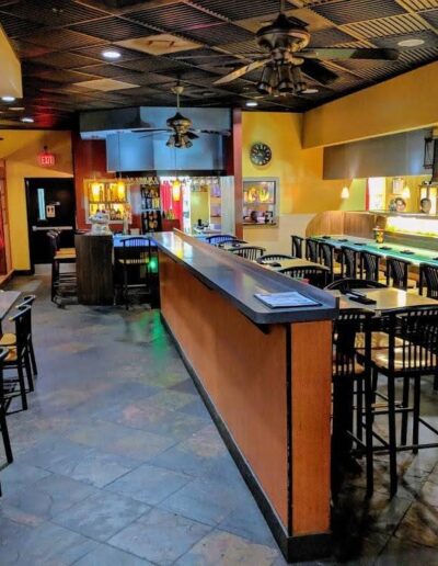 An empty restaurant interior with a bar and tables set for dining.