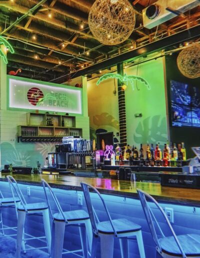 Vibrant beach-themed bar with stools and neon lights.